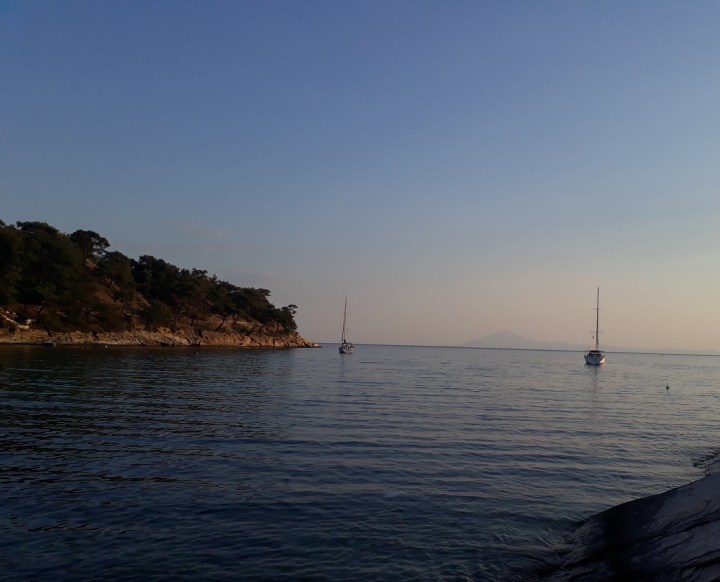 Two boats anchored in Alyki Bay in Thassos Island. You can see Mount Athos in the background